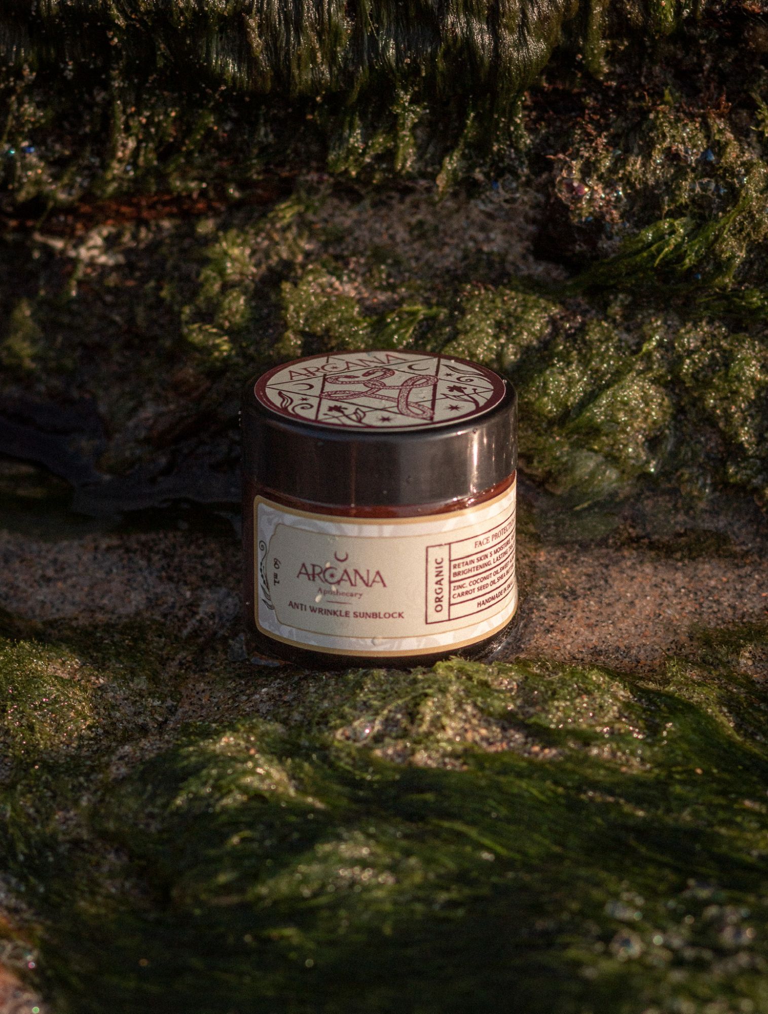 ARCANA Sunblock jar resting on mossy coastal rock